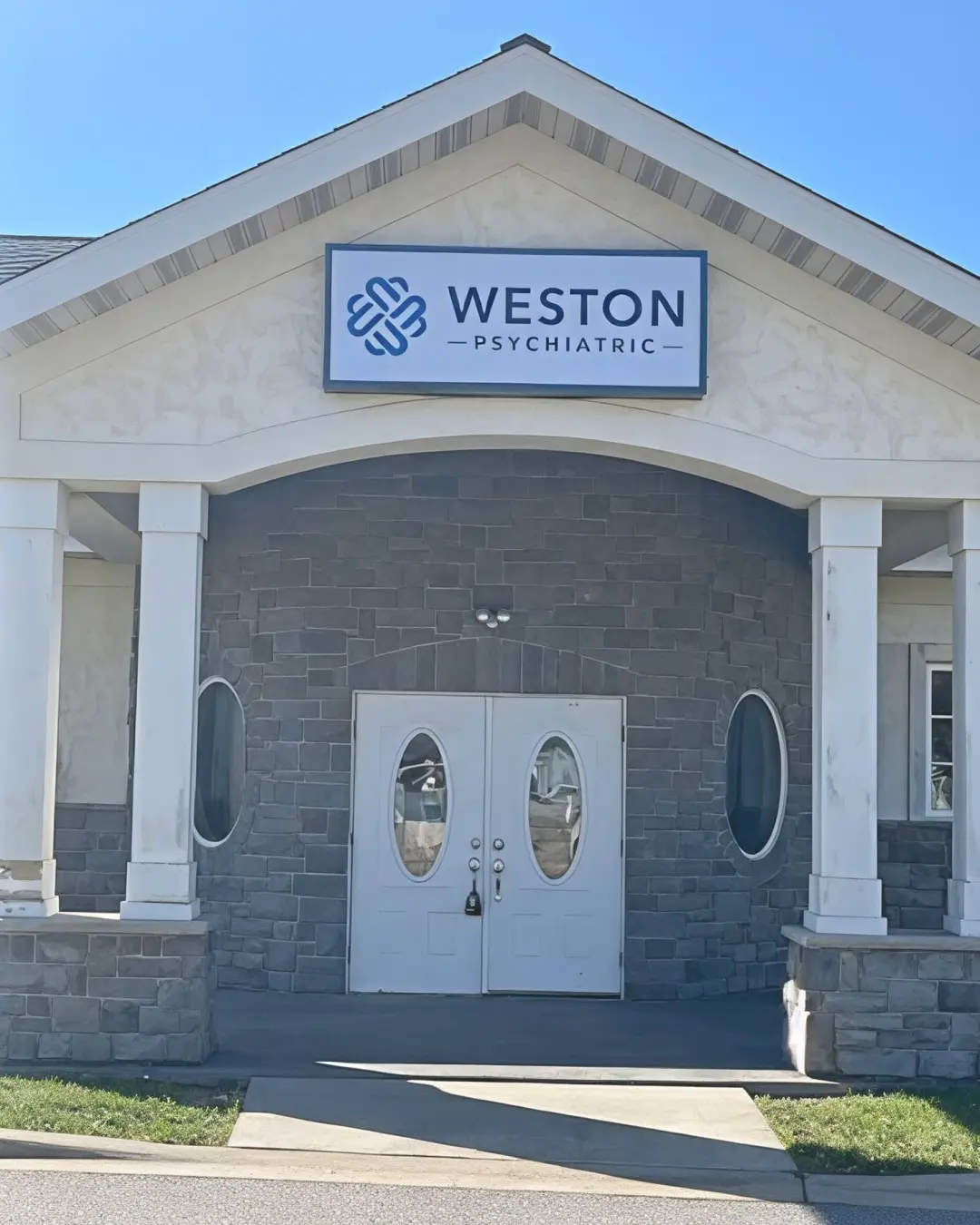 Weston Psychiatric front entrance before: streaked cream stucco, white double doors and white window frames.